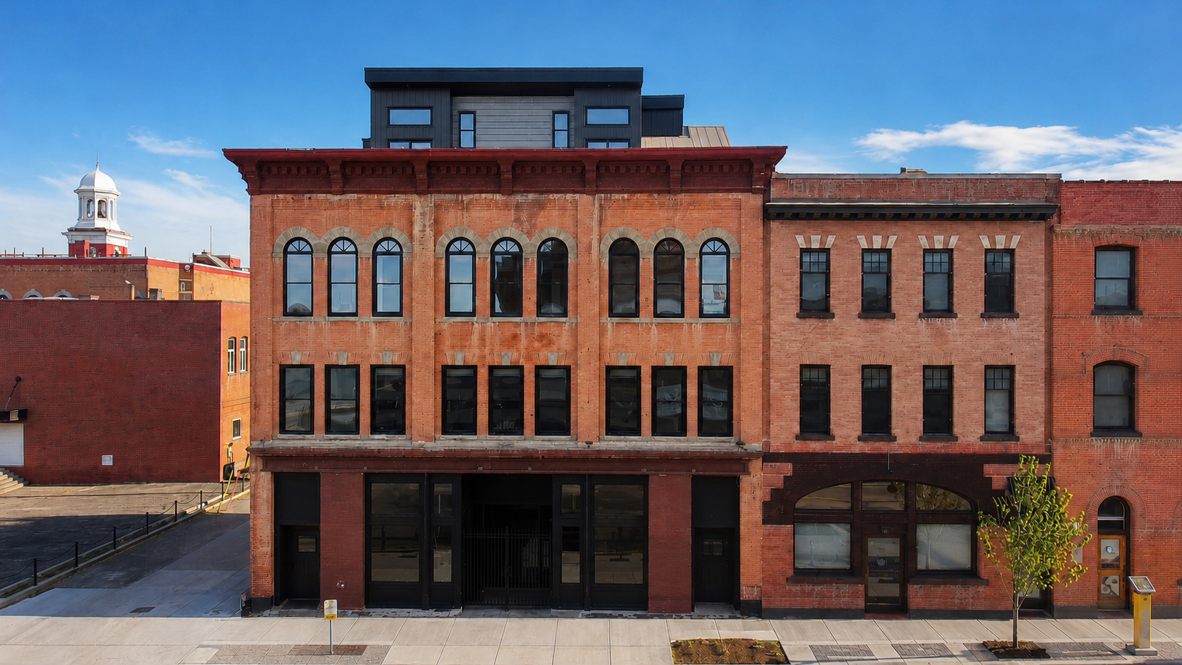 The Whitney Block, a restored 1907 heritage building in downtown Lethbridge showing the full brick facade with arched windows and modern penthouse addition